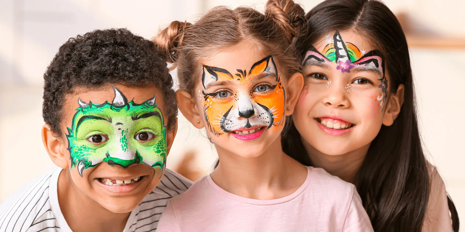Three smiling children with dragon, fox and unicorn face paint