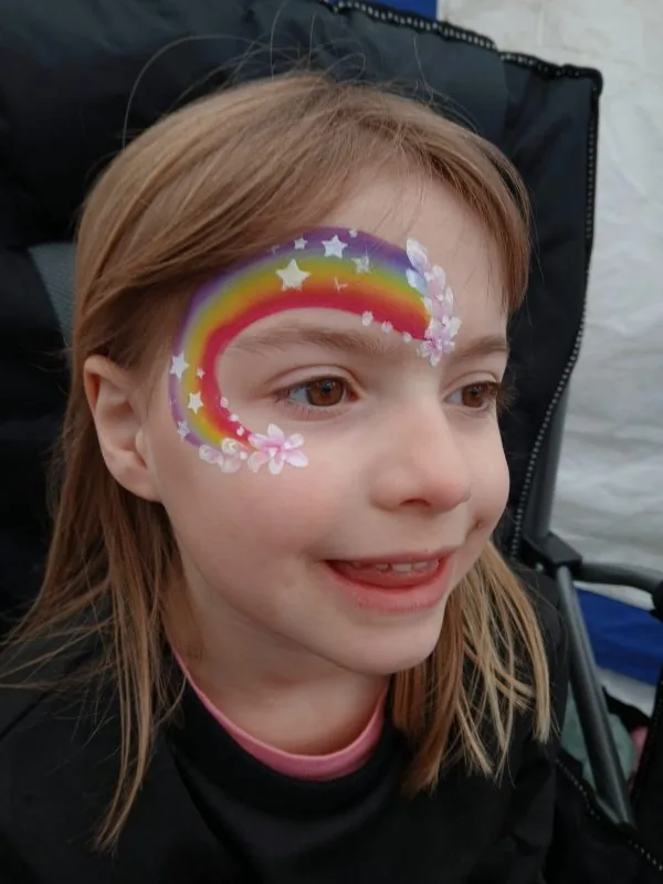 Child with rainbow and star face paint